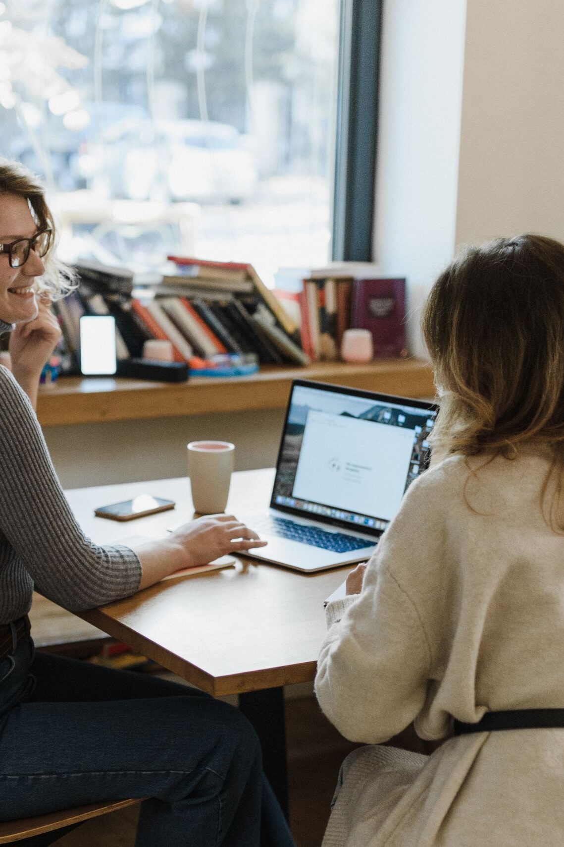 Two women engaging in a collaborative work session at an office desk with a laptop.